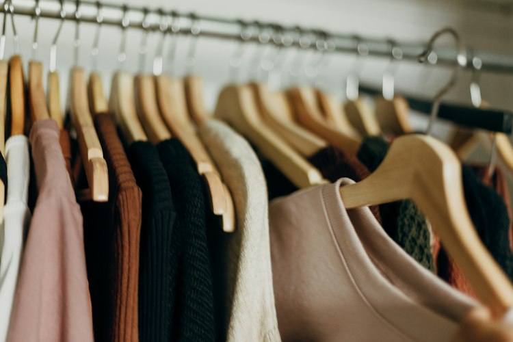 A smartphone screen displaying outfit suggestions laid out next to an open wardrobe