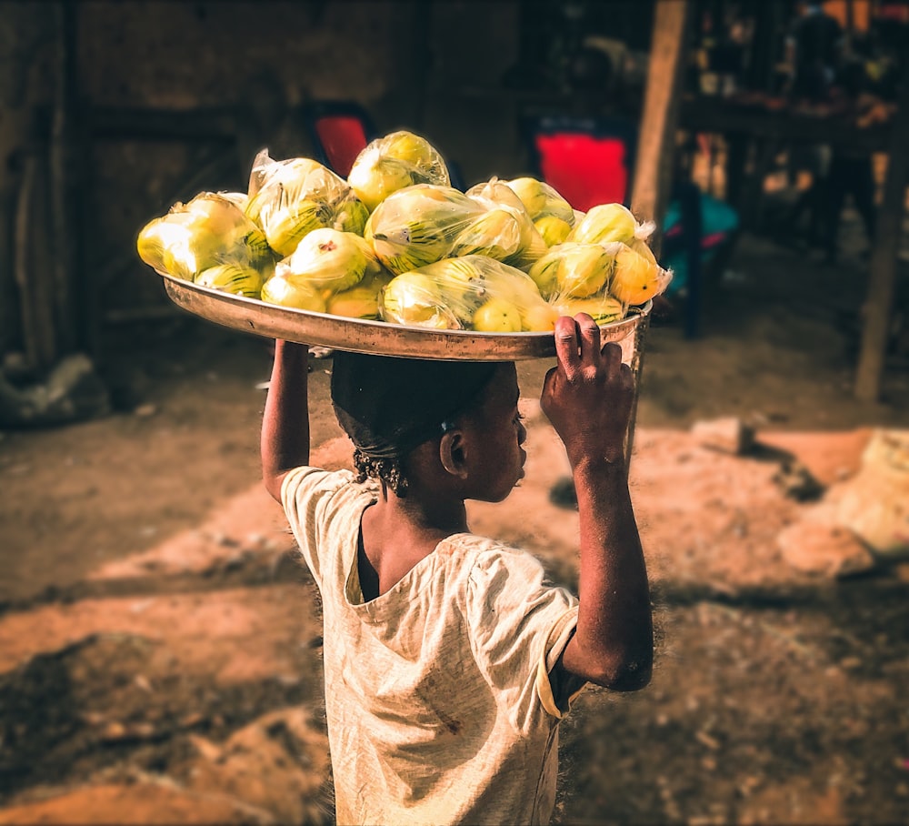 a person carrying a tray of fruit