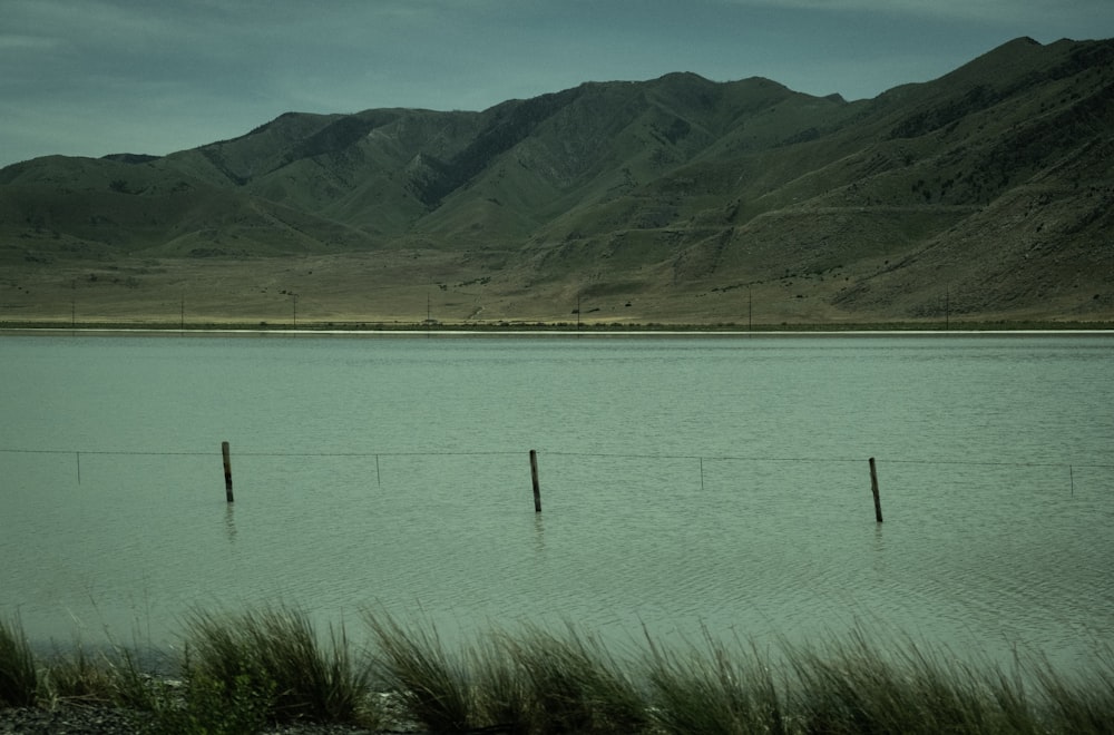 a body of water with a fence and mountains in the background