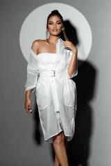 Elegant woman wearing a stylish belt, standing confidently with soft beige and gold tones in the background.