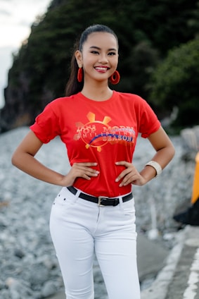 A vibrant young woman wearing a bold graphic t-shirt, smiling confidently outdoors.