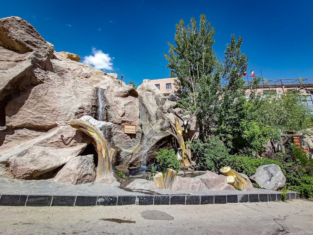 a large rock formation with trees and a building in the background