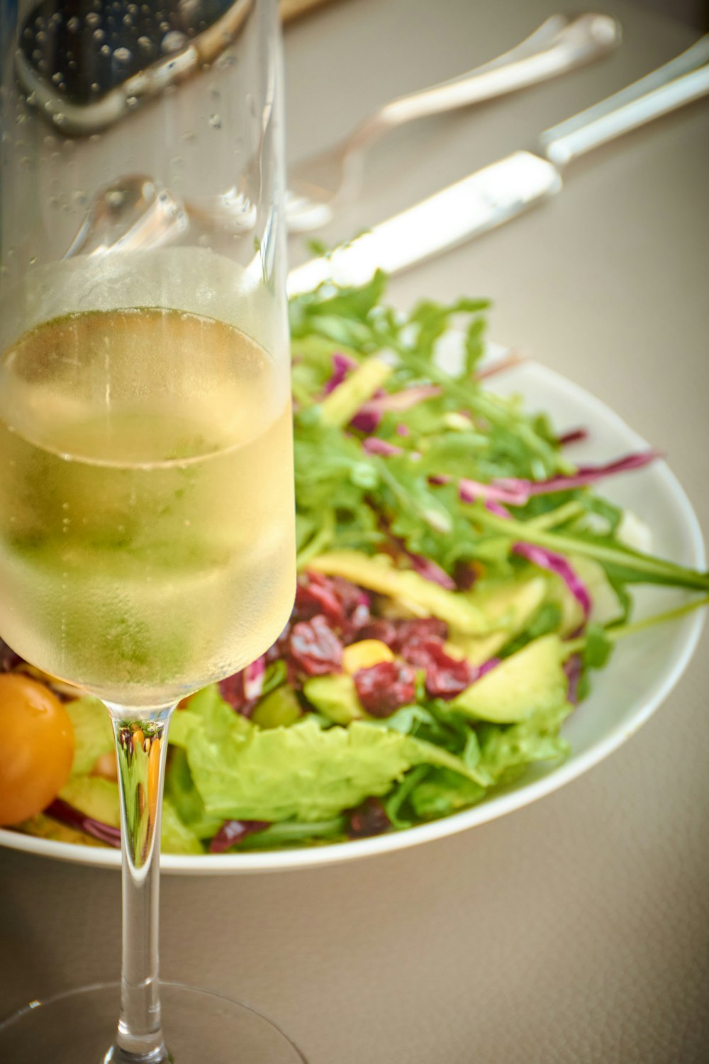 a glass of champagne next to a salad