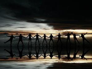 A vibrant sunset behind a circle of people holding hands, embodying unity and freedom.