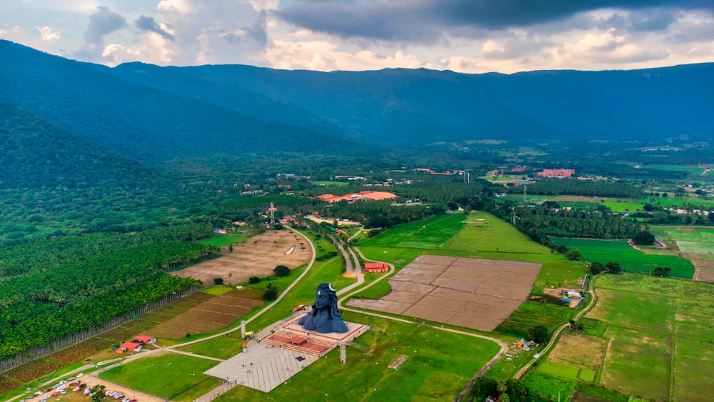 a landscape with a statue and a road with trees and hills in the background