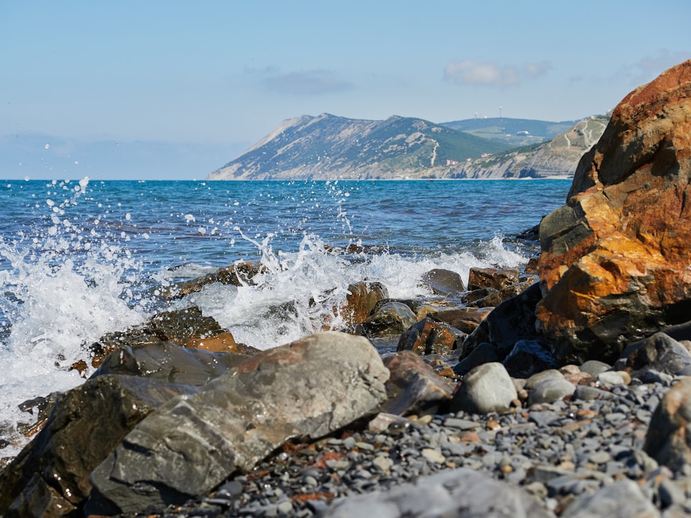 a rocky beach with a mountain in the background