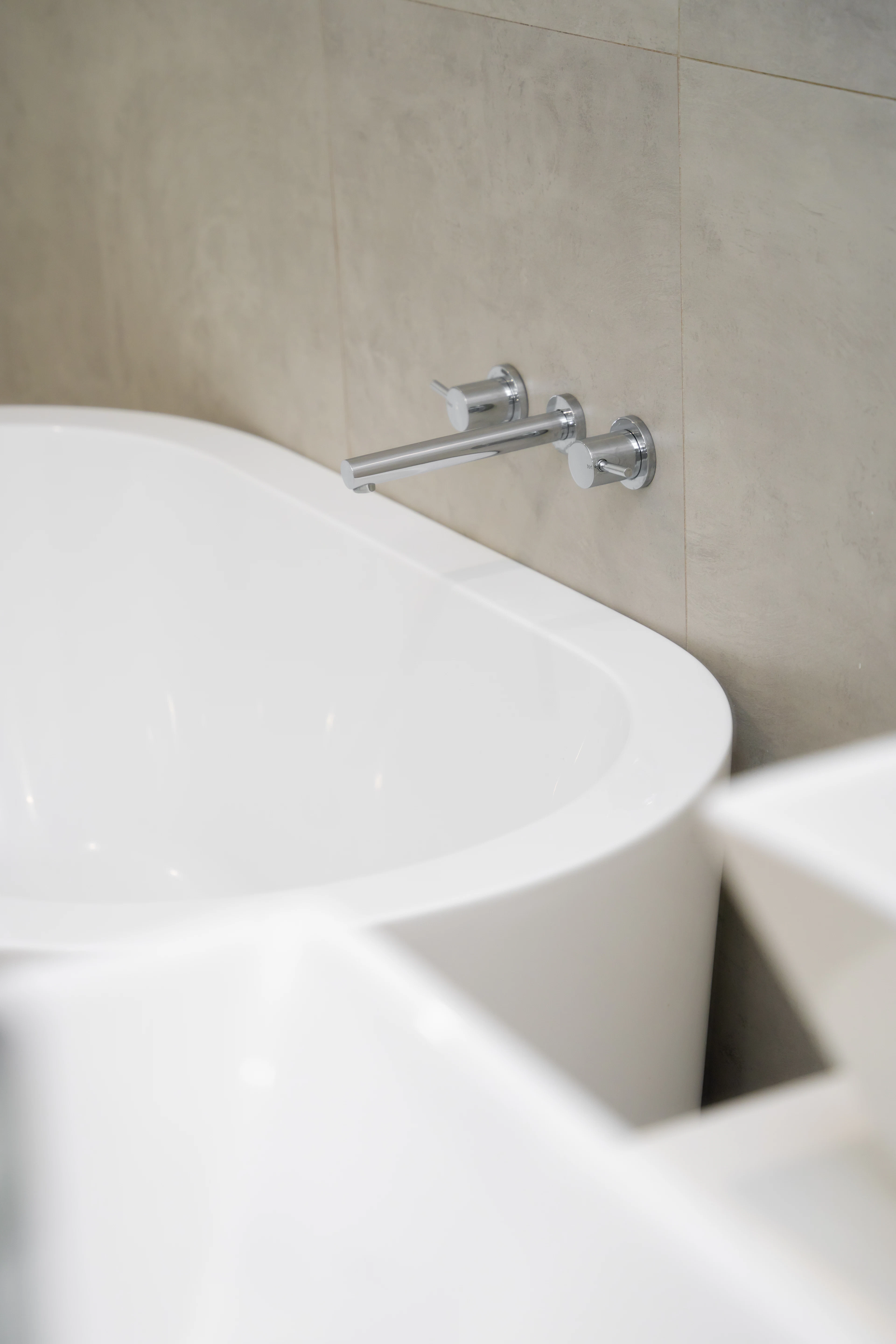 Wall-mounted tub filler over a freestanding tub