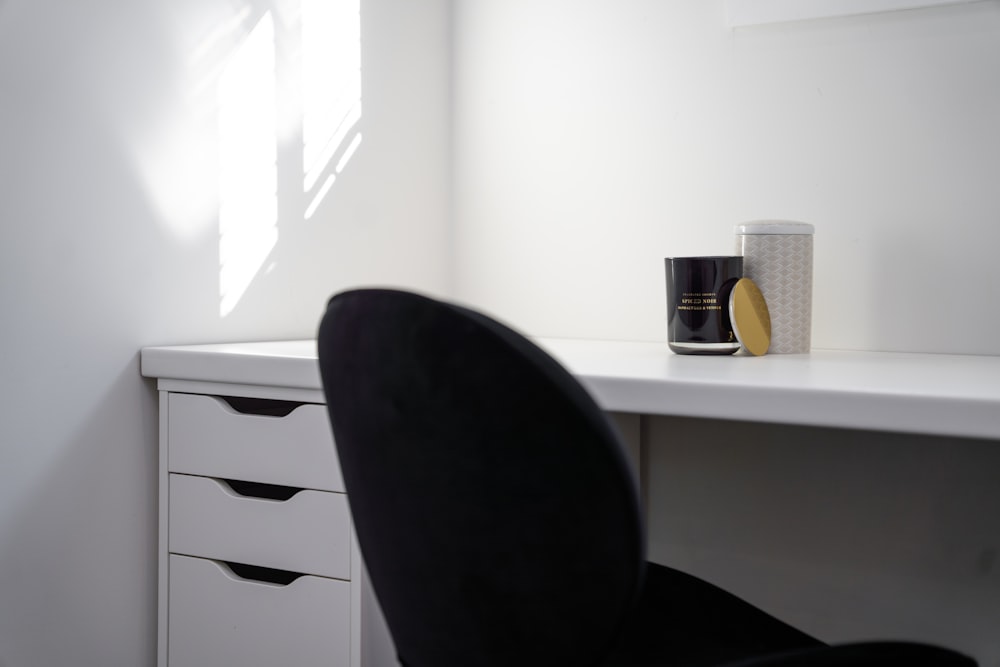 a black chair in front of a white wall with coffee cups