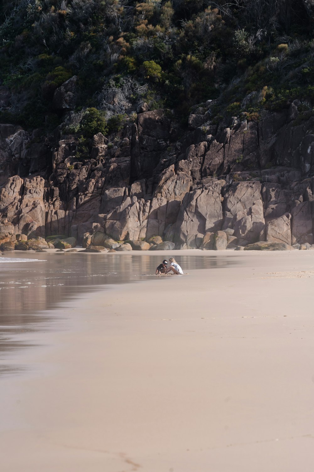 a couple people on a boat in a body of water by a rocky cliff