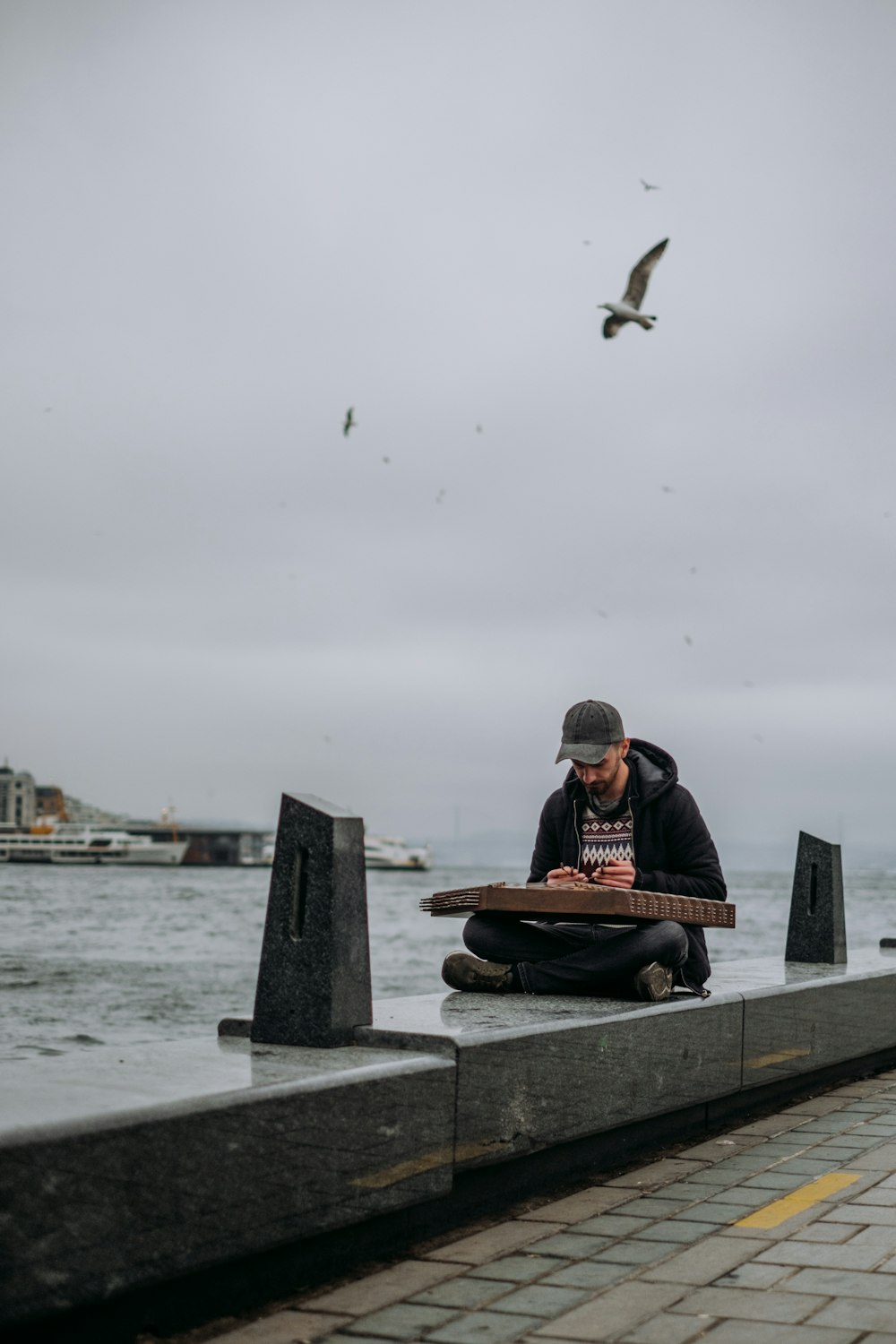 a man sitting on a bench with a laptop in front of a body of water