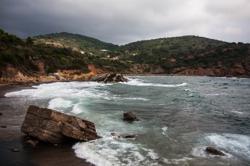 a rocky beach with a hill in the background