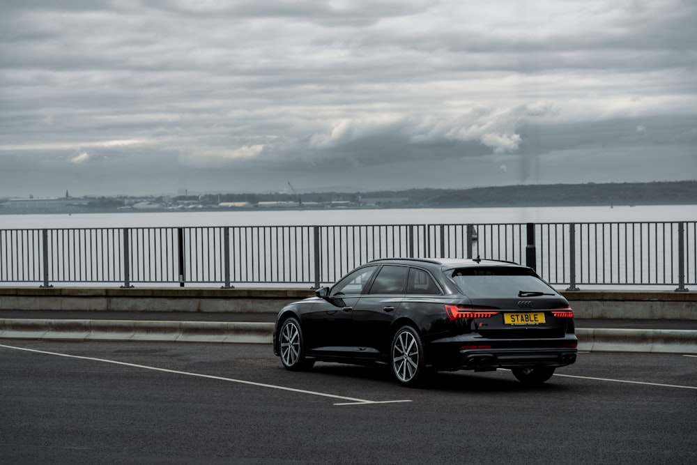 a black car on a road by a body of water