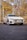 A sleek, white Volkswagen car with an elegant design is parked on a smooth asphalt surface. The vehicle has modern alloy wheels and a custom license plate reading 'STABLE'. Surrounding the car are autumn trees with yellow and brown leaves, and a large building backdrop.