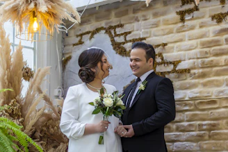 A couple exchanging vows in a warmly lit hotel ballroom with elegant floral decor.