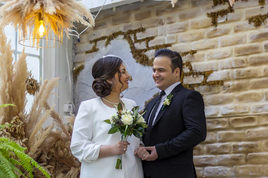 A couple exchanging vows in a warmly lit hotel ballroom with elegant floral decor.