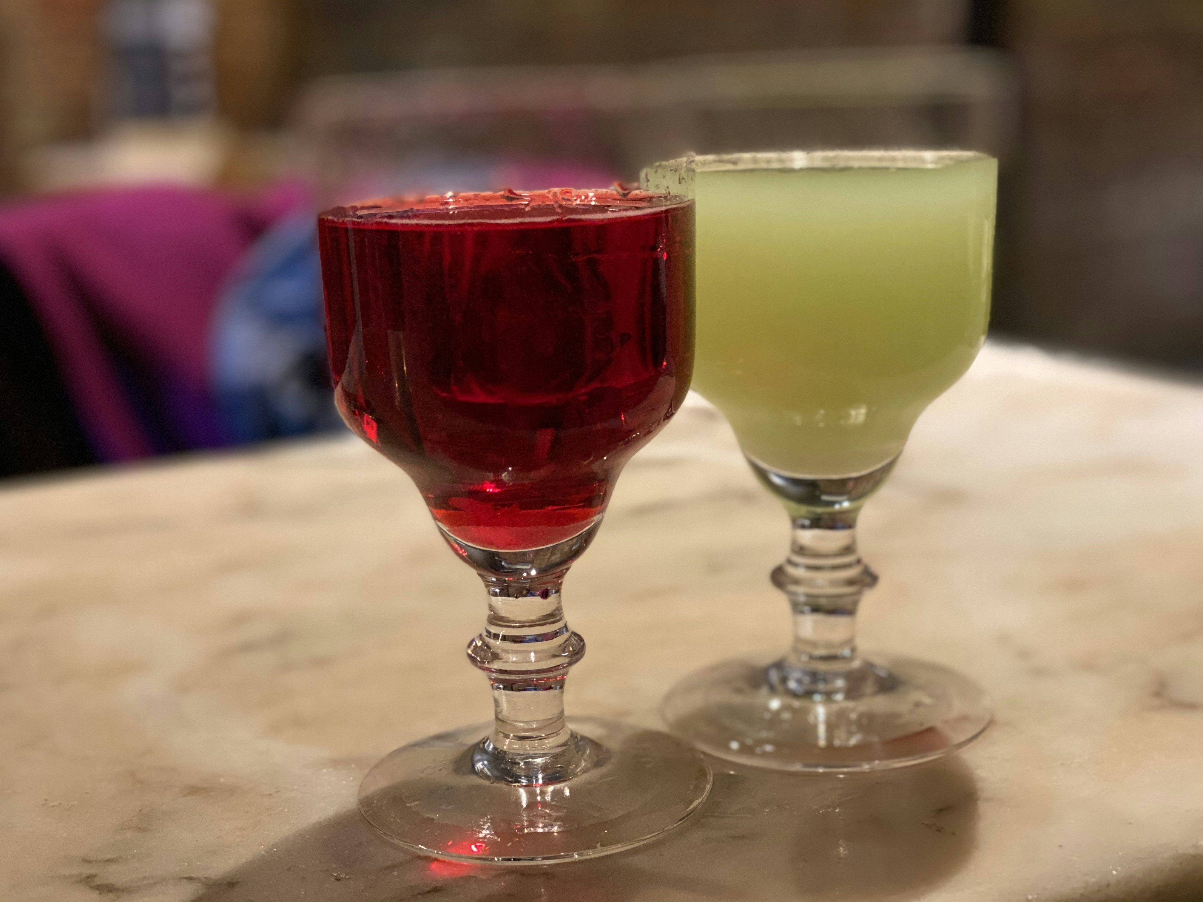 a couple of glasses with colorful drinks, 