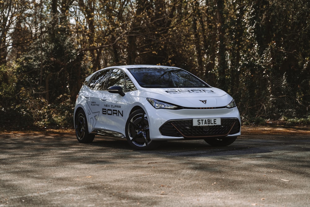 a white car on a road with trees in the background