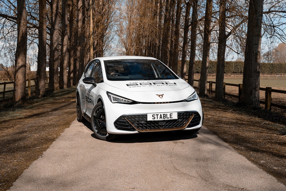 a white car on a road with trees on either side of it