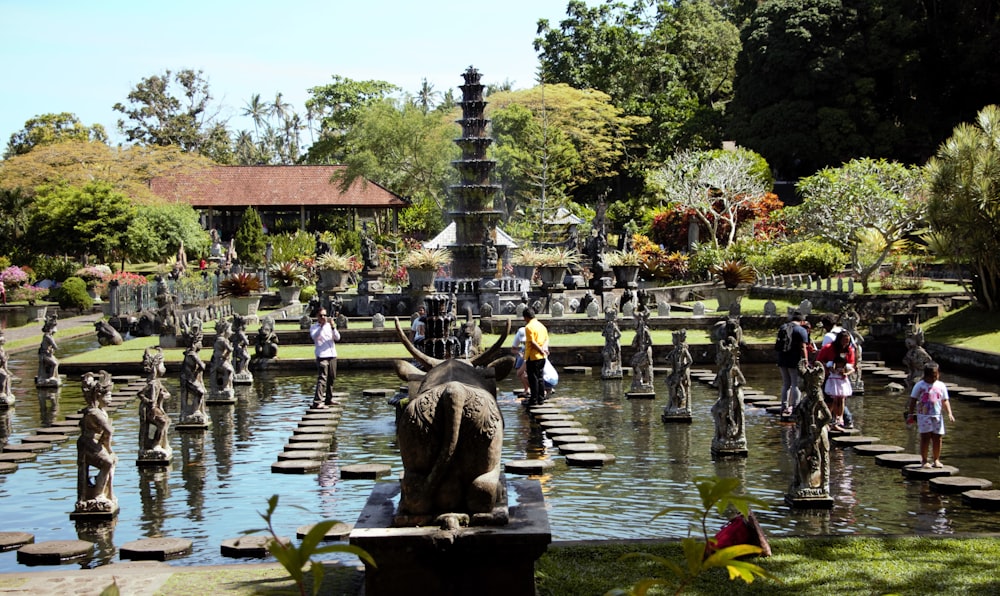 a group of people standing around a fountain with statues in it