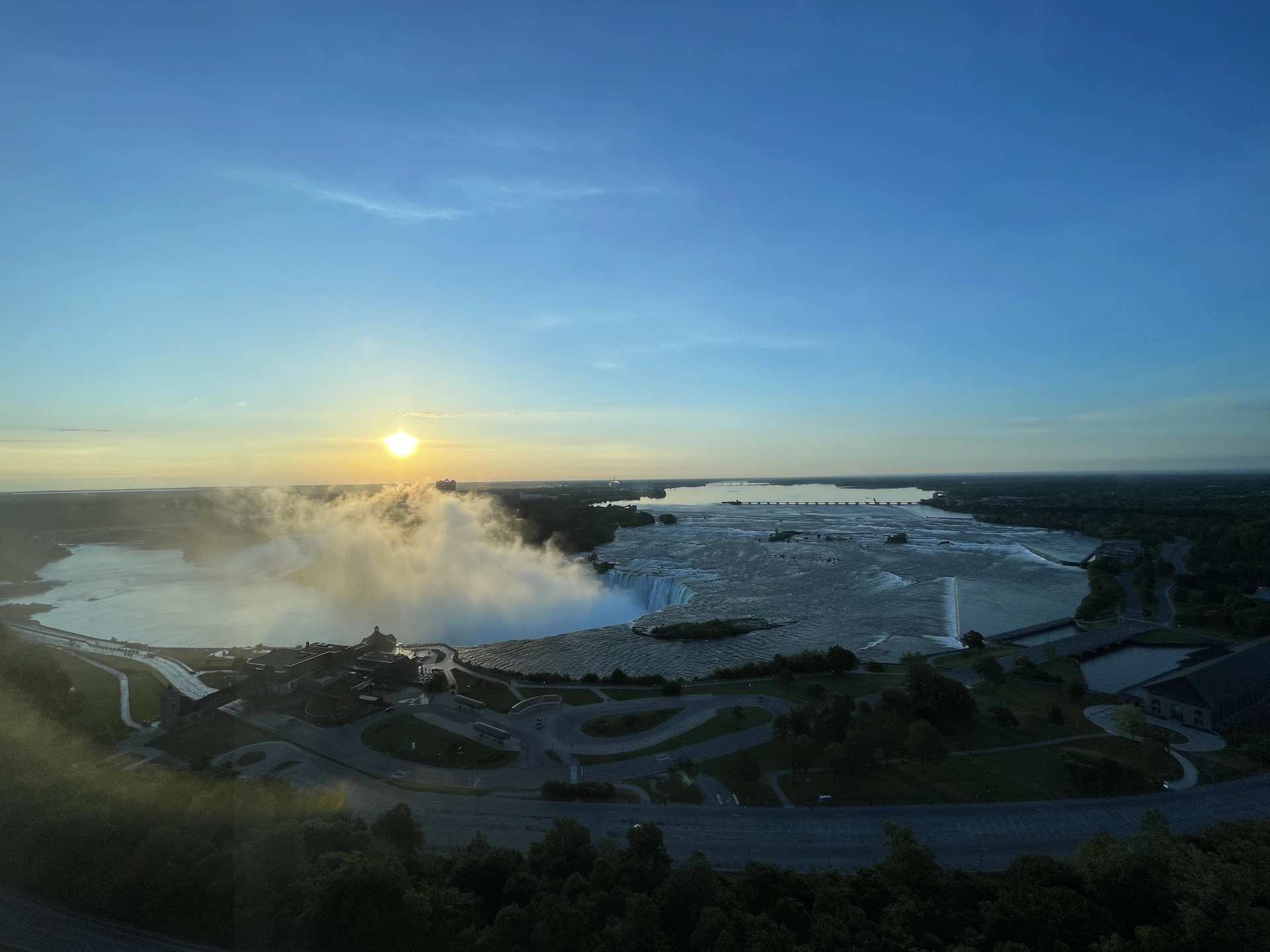 A breathtaking aerial view of Victoria Falls with mist rising above the cascading water under a golden sunset.