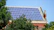 A cozy home roof featuring colorful semi-transparent photovoltaic tiles glowing under sunlight.