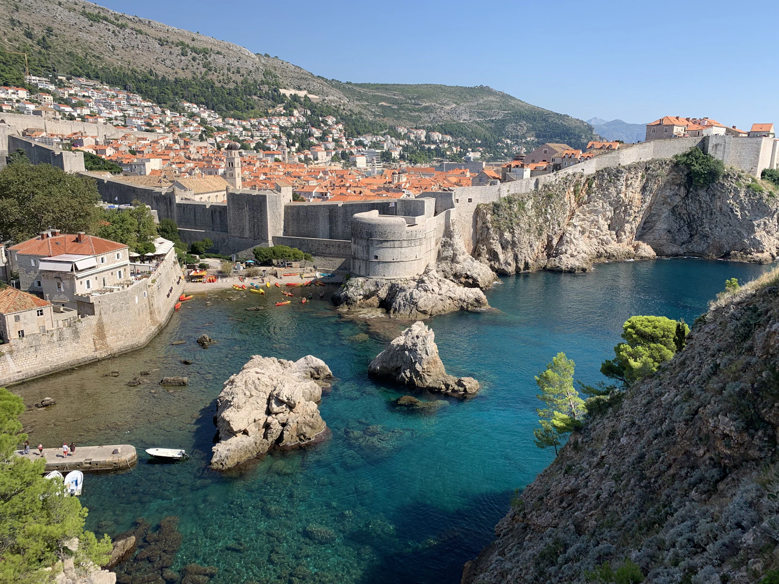 Dubrovnik's medieval city walls and Bokar fortress above the clear turquoise water of Kolorina bay