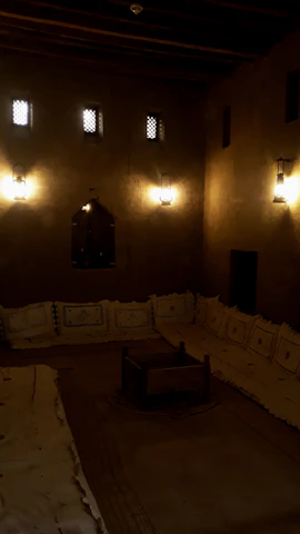 A warmly lit dining room with royal blue and gold decor, glowing lanterns casting soft shadows over a table set with traditional Moroccan dishes.