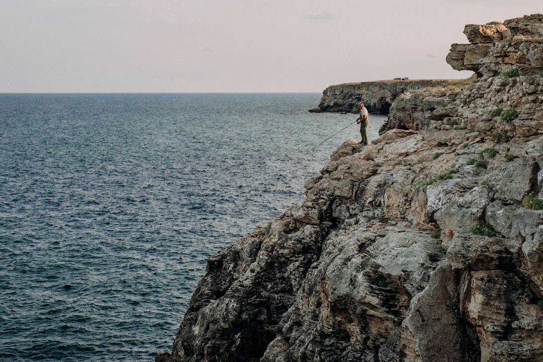 a person standing on a cliff above the ocean with Bempton Cliffs in the background,