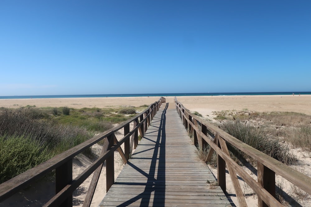 a wooden bridge over a sandy beach