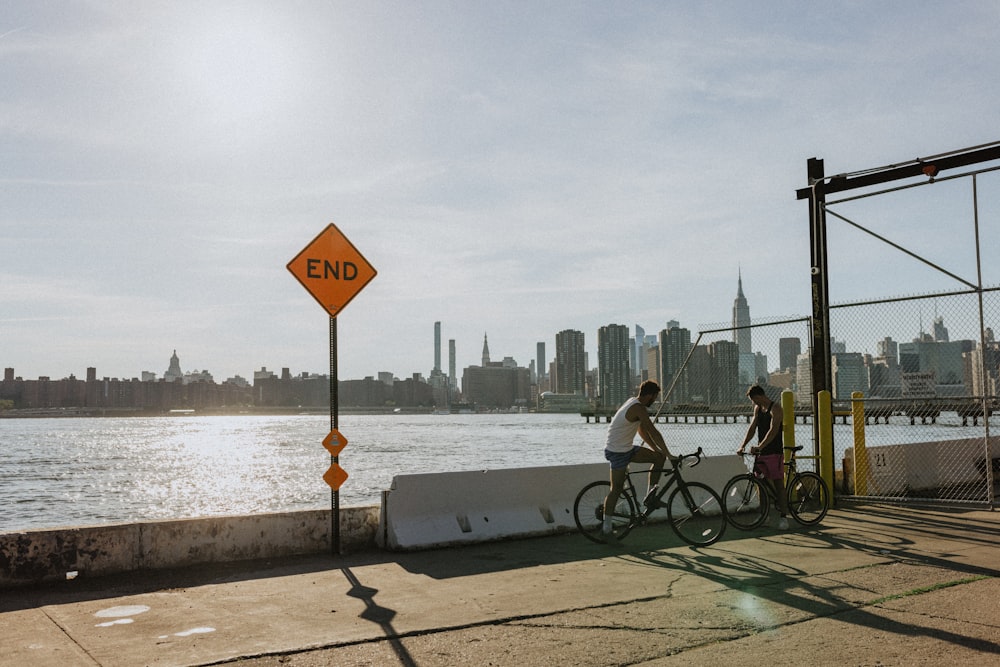 a couple of people ride bikes down a sidewalk