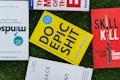Several books placed on a grass surface, including titles like 'Mindsight,' 'Do Epic Shit,' and 'Skill Kill.' The covers of the books are visible, with varying colors including yellow, red, and blue. The books are arranged in a casual, overlapping manner.