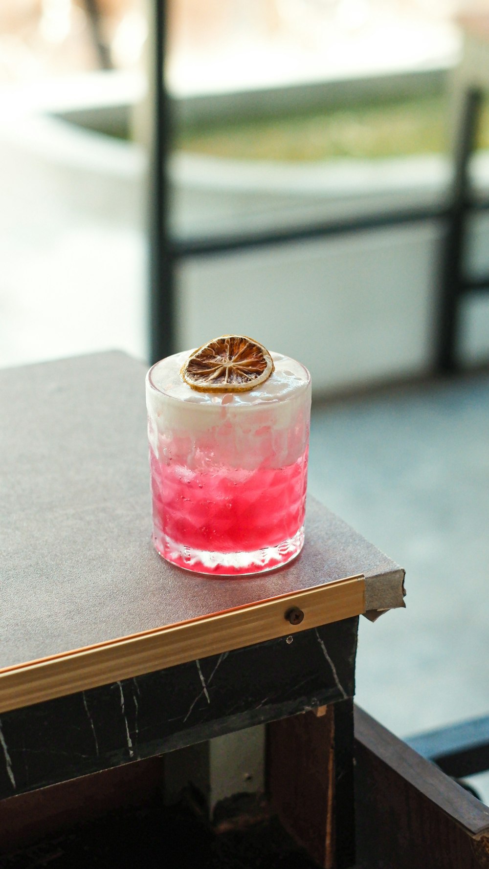 a glass of pink liquid with a brown object on top