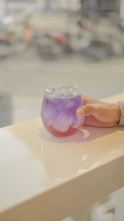 a hand holding a glass of liquid