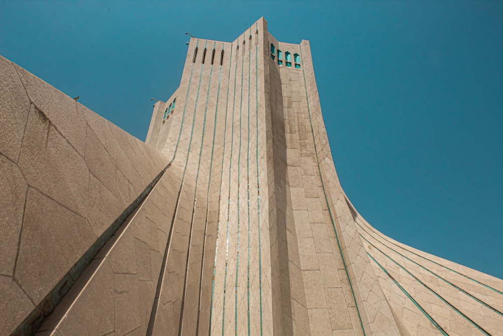 a tall stone building with Azadi Tower in the background