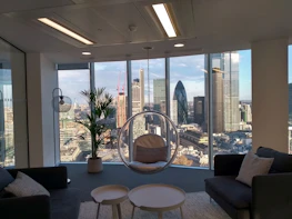 A modern office space with floor-to-ceiling windows overlooking a city skyline at dusk.