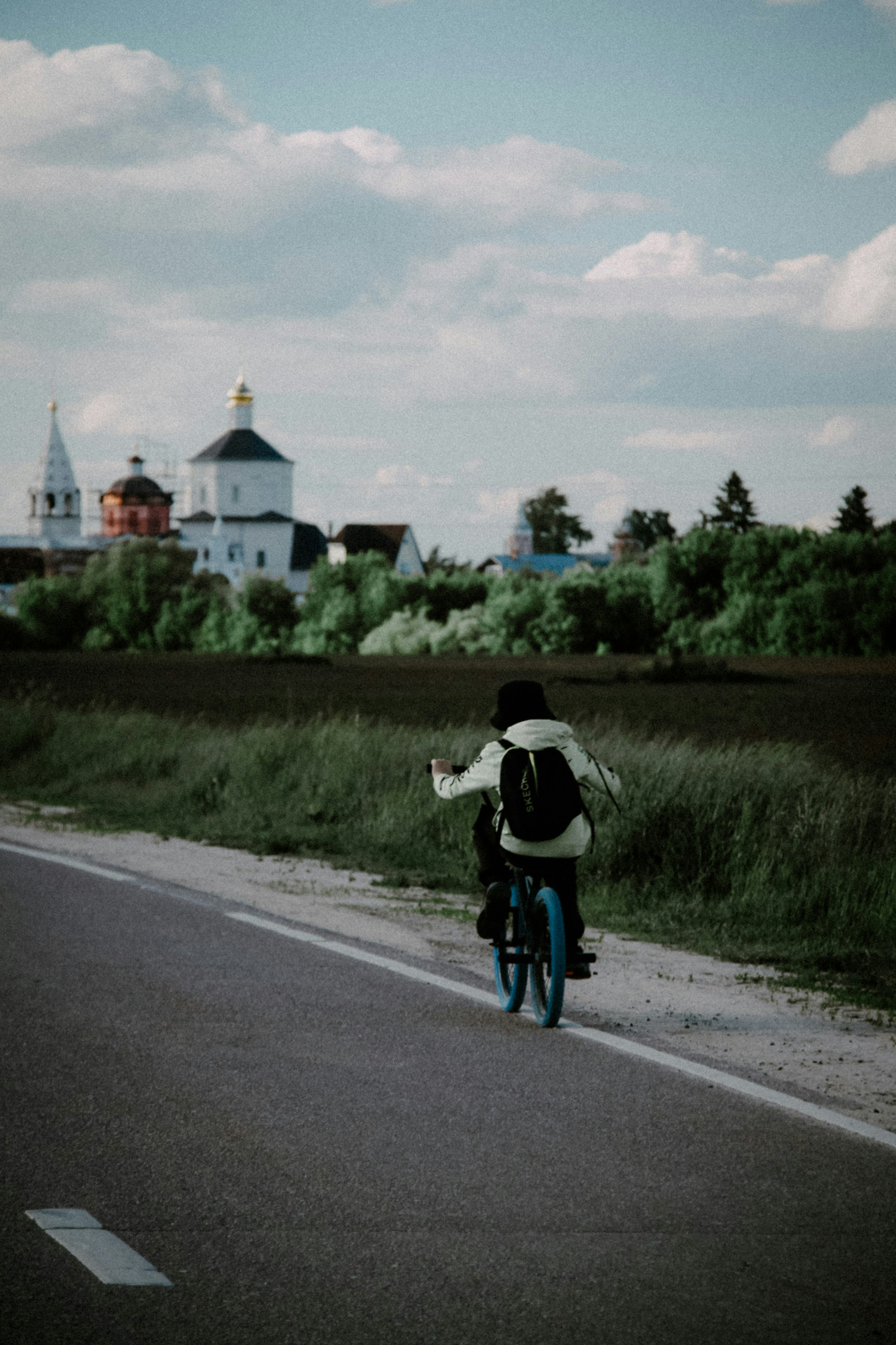 a person riding a bicycle on a road with a building in the background