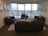 A bright and modern living room with large windows and stylish furniture, showcasing a comfortable apartment interior.
