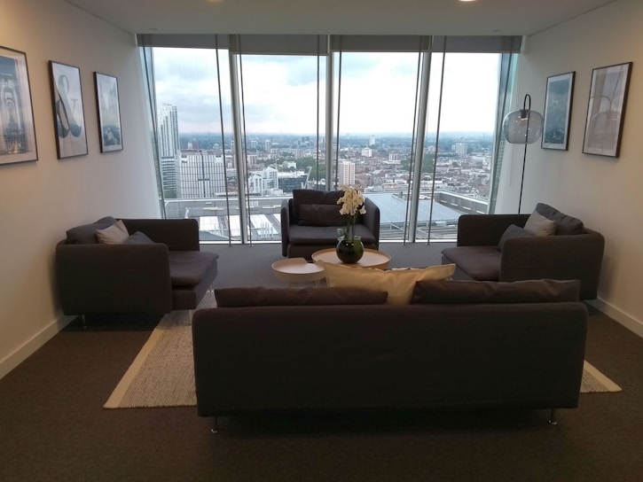 A stylish modern living room in a flagship n k group property, with floor-to-ceiling windows and tasteful decor.