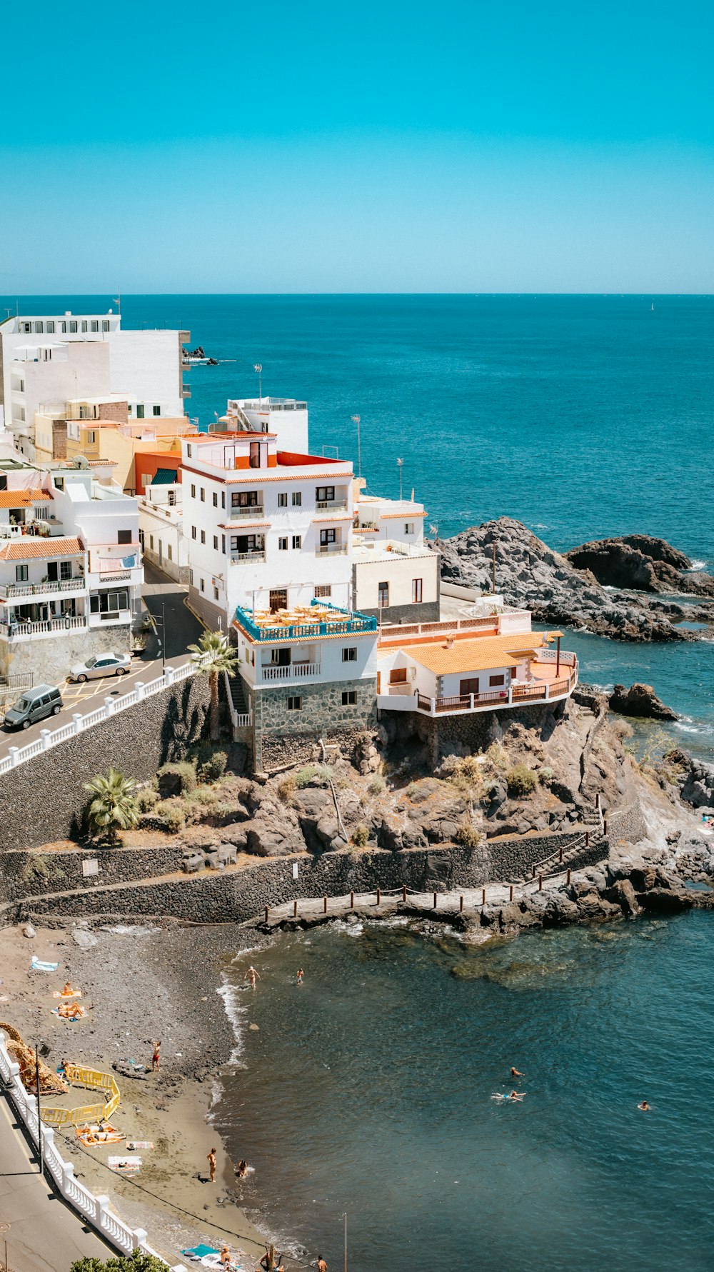 a group of buildings on a rocky beach by the water