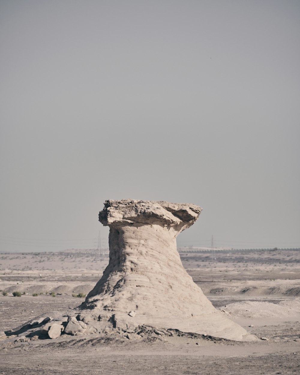 a large rock formation in the middle of a sandy area