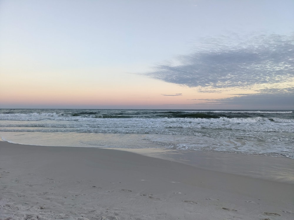 a beach with waves and a cloudy sky