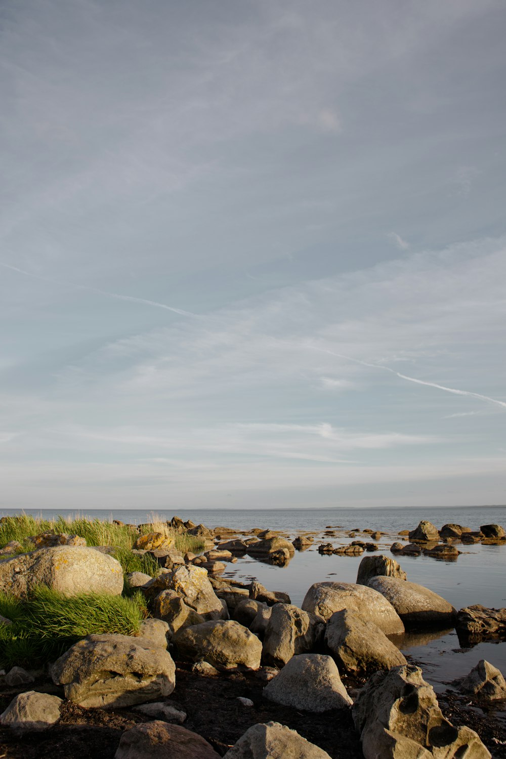 a rocky beach with water and clouds