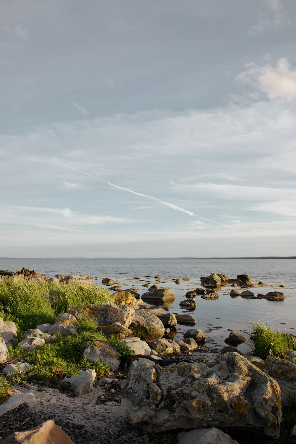 a rocky beach with water and clouds