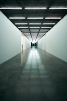 A cinematic hallway featuring clean lines and minimalist architecture, illuminated with subtle ambient lighting.