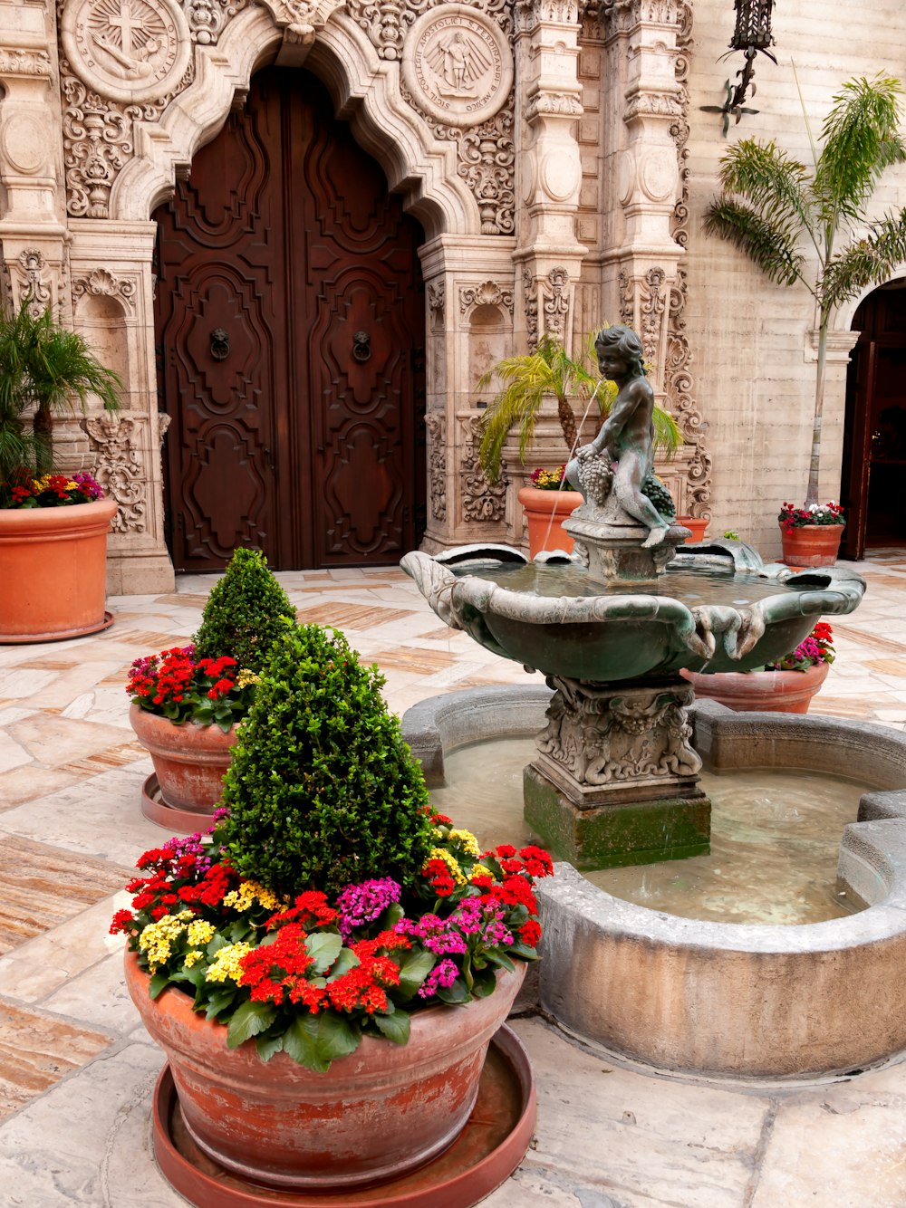 a fountain with flowers and a statue in the middle