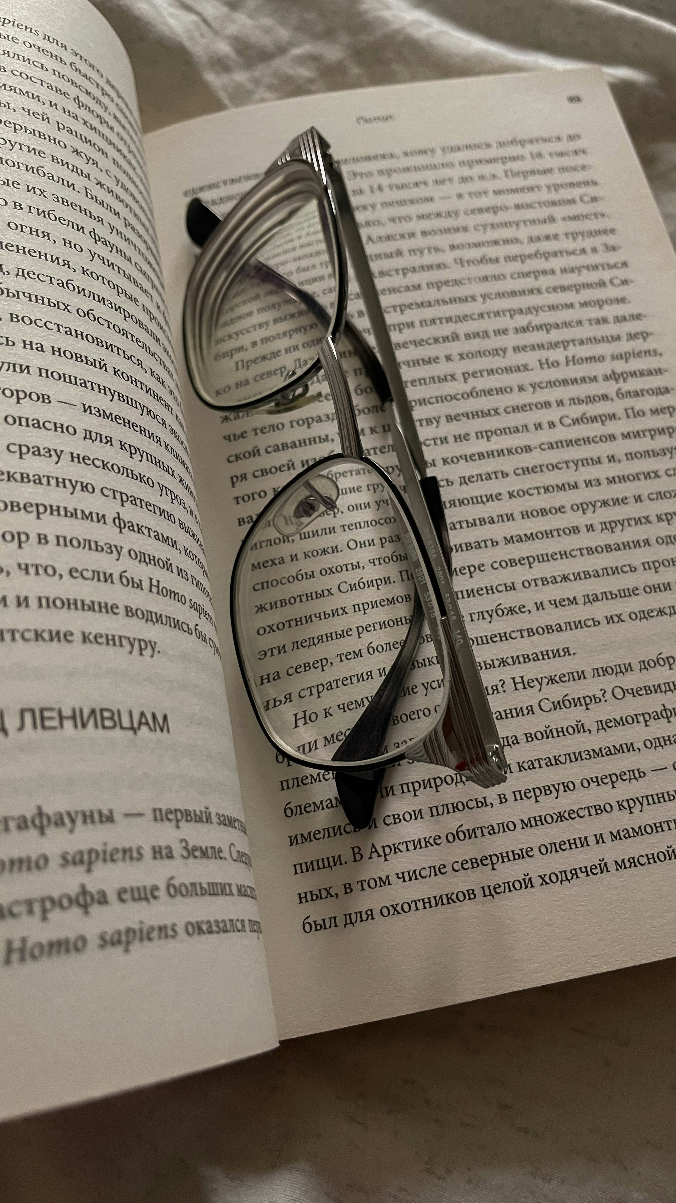 Open book with dense academic text, reading glasses resting on the page