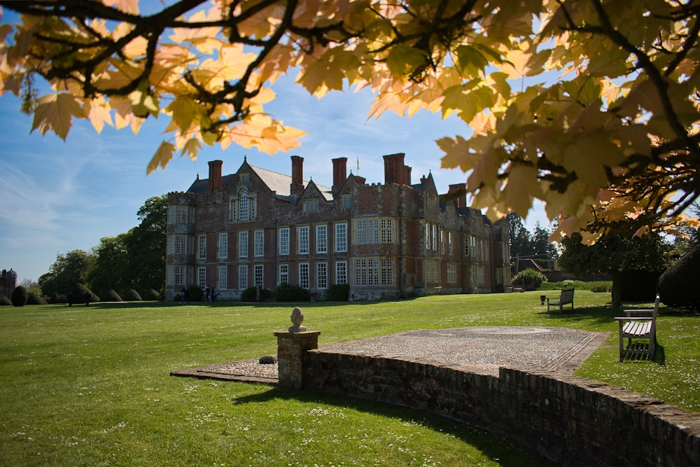 a large building with a lawn and benches in front of it with Loseley Park in the background