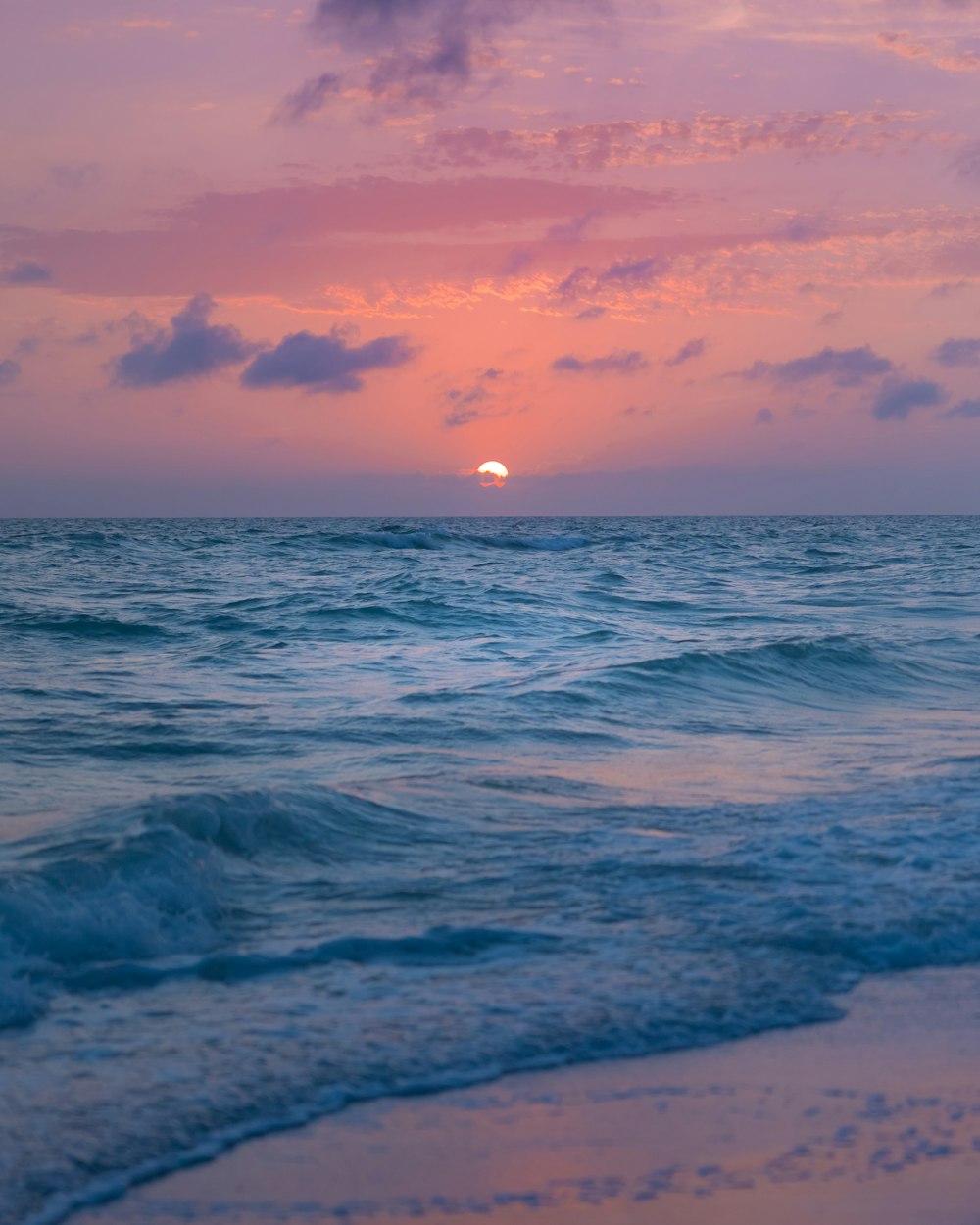 a beach with waves and a sunset