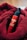 A red bottle labeled 'MARO 17 COLLAGEN SHOT' is nestled in a soft, textured red fabric. The bottle features a pump top, and the vibrant red of the fabric complements the glossy finish of the bottle.