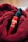A red bottle labeled 'MARO 17 COLLAGEN SHOT' is nestled in a soft, textured red fabric. The bottle features a pump top, and the vibrant red of the fabric complements the glossy finish of the bottle.